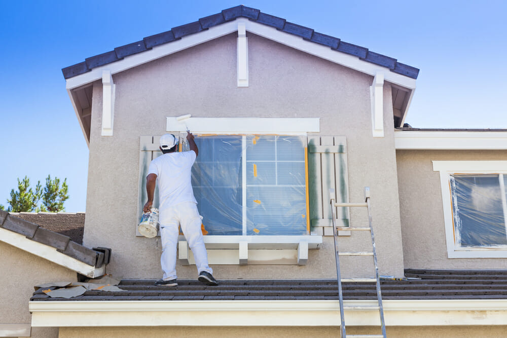 Busy House Painter Painting the Trim And Shutters of A Home. Busy House Painter Painting the Trim And Shutters of A Home.