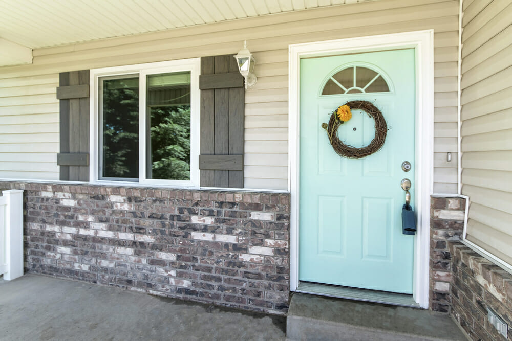 Entrance of a house with brick walls and vinyl siding